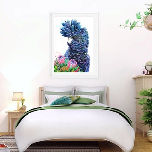 Puede incluir: Una pintura de acuarela de un cacat&uacute;a negro con plumaje azul y verde, posado entre flores de protea rosas y verdes. El p&aacute;jaro est&aacute; mirando hacia la izquierda de la imagen.