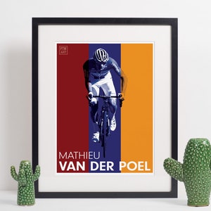 Puede incluir: Un póster enmarcado con un fondo azul, rojo y naranja que presenta a un ciclista con un maillot blanco y azul montando una bicicleta. El póster tiene el texto "MATHIEU VAN DER POEL" en la parte inferior.