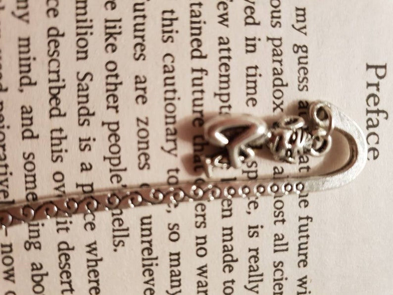 Op de afbeelding: Zilveren bladwijzer met een hart, een vlinder en een decoratief ontwerp. De bladwijzer ligt op een pagina van een boek met het woord "Voorwoord" bovenaan de pagina.