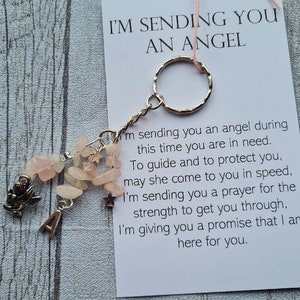 May include: A pink and silver keyring with a charm that says "I'm sending you an angel". The charm is attached to a pink string and a silver key ring. The keyring also has a small silver charm with the letter "A" on it.