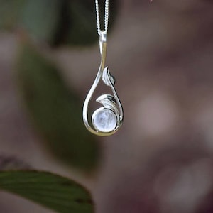 May include: A silver pendant necklace with a moonstone set in a leaf design.