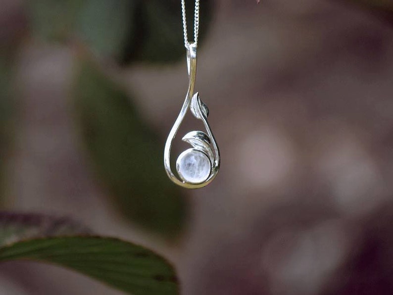 May include: A silver pendant necklace with a moonstone set in a leaf design.