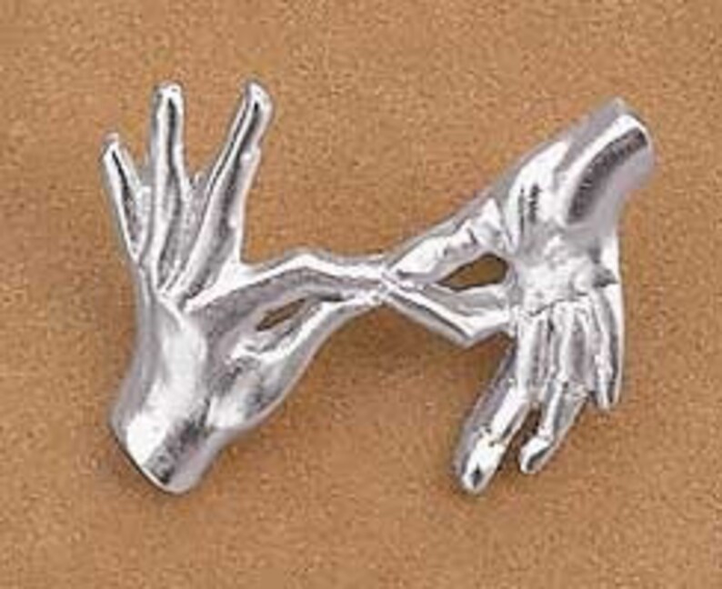May include: Silver-toned brooch depicting two hands intertwined, symbolising love and unity.