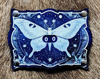 May include: A blue leather patch with a white butterfly design and a white number "00" in the center. The butterfly is surrounded by stars and other decorative elements.