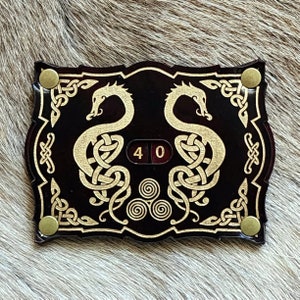 Könnte beinhalten: Ein schwarzer und goldener Holz-Zähler mit zwei goldenen Drachen auf jeder Seite eines roten und weißen Zahlen-Zählers, der "40" anzeigt.