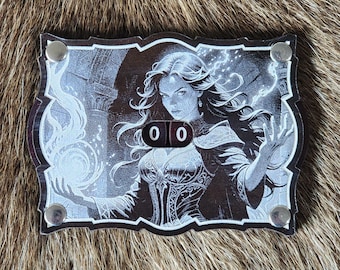 May include: A wooden counter with a white and black image of a woman with long dark hair, holding a glowing orb. The counter has a black and white number display that reads "00".