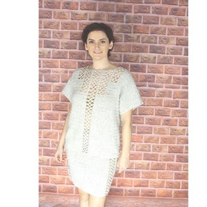 May include: A crochet top with a lace column design. The top is white and is shown on a model against a brick wall. The pattern is labeled "435 Lace Columns Top" and is described as "easy".
