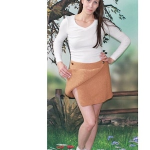May include: A brown crocheted wrap skirt with buttons. The skirt is shown on a model wearing a white long-sleeved shirt. The image includes the text "707 Buttoned Wrap Skirt", "Materials: #3 Light worsted/sport weight yarn or baby yarn. Crochet hook size 'F', or size to give correct gauge. Two ¼" buttons of color choice.", and "Sizes: Directions for all sizes are the same. The Finished size will be determined by starting ch. EASY".