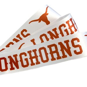 May include: White satin ribbon with the words "Longhorns" printed in orange. The ribbon also features a stylized orange Longhorn steer head.