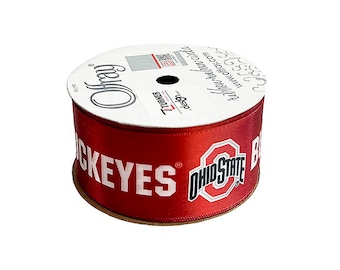 May include: A spool of red satin ribbon featuring the words "BUCKEYES" and "OHIO STATE" in white. The ribbon is from Offray and has a white label with text and a QR code.