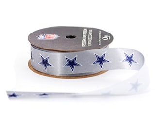 May include: A roll of silver satin ribbon with blue star designs. The ribbon is on a brown cardboard spool with the text "DECORATIVE RIBBON ONLY DECORATIVE" printed on the spool.