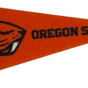 May include: Orange pennant with black text and graphics. The pennant features the Oregon State University logo, a stylized beaver head, and the words "OREGON STATE" in bold letters. A black stripe runs along the left edge.