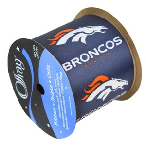 Könnte beinhalten: Eine Rolle marineblaues Band mit dem Logo der Denver Broncos in Weiß und Orange. Das Band ist mit "Offray" beschriftet und enthält Text in mehreren Sprachen, darunter "Ribbon" und "Cinta."