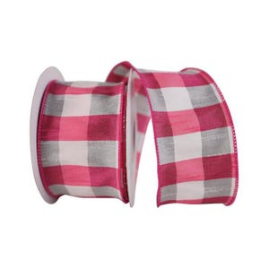 May include: A spool of wired ribbon featuring a repeating buffalo check pattern in shades of bright pink, white, and light gray. The fabric has a visible woven texture with finished edges, and the ribbon is wound around a central white plastic core.