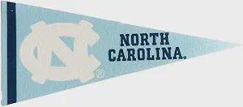 May include: Light blue pennant with the words "NORTH CAROLINA" in dark blue text. The pennant features a large white interlocking "NC" logo. A dark blue vertical stripe is on the left side of the pennant.