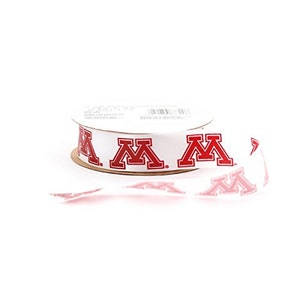 May include: White ribbon with a red University of Minnesota "M" logo repeated on the ribbon. The ribbon is rolled up on a cardboard spool.