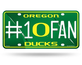May include: Green and yellow metal license plate with the text "Oregon" and "#1 O FAN DUCKS" in white. The "O" in "FAN" is a yellow and green Oregon Ducks logo.