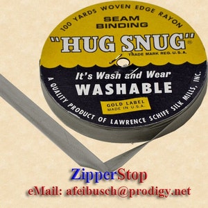 以下が含まれることがあります： グレーの縫い付け用バイアステープのロール。黄色のラベルには、「Hug Snug」Seam Binding、100ヤード、Woven Edge Rayon、Trade Mark Reg. U.S.A.、It's Wash and Wear、Washable、Gold Label Made in U.S.A.、A Quality Product of Lawrence Schiff Silk Mills, Inc.と記載されています。
