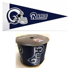 May include: A blue and white pennant with the Los Angeles Rams logo and the text "Los Angeles Rams". A roll of blue and white ribbon with the Rams logo and the text "Rams" is also shown.