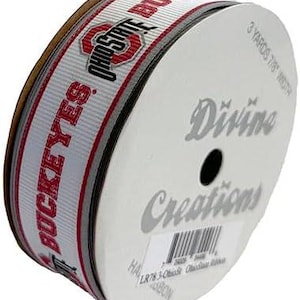May include: A roll of white and gray ribbon with the Ohio State Buckeyes logo and the text "Ohio State Buckeyes" in red. The ribbon is 3 yards long and 1.75 inches wide. The label on the roll says "Divine Creations".