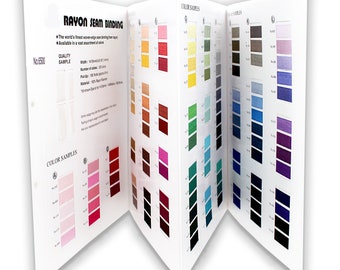 Op de afbeelding: Een open wit boekje met kleurstalen van rayon naadband. Het boekje toont meerdere pagina's met kleurstalen in verschillende tinten, waaronder roze, rood, geel, groen, blauw en paars. De tekst op de omslag luidt "RAYON SEAM BINDING".
