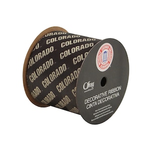 May include: A roll of black and tan decorative ribbon with the words "Colorado" printed in tan on the ribbon. The ribbon is on a spool with a black label that says "Officially Licensed Collegiate Product" and "Decorative Ribbon Cinta Decorativa".