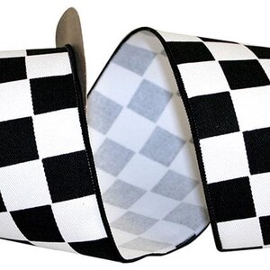 May include: A wide spool of fabric ribbon featuring a repeating black and white checkered pattern. The ribbon is wound around a cardboard core and displays a consistent grid of alternating square blocks across its entire visible surface area.