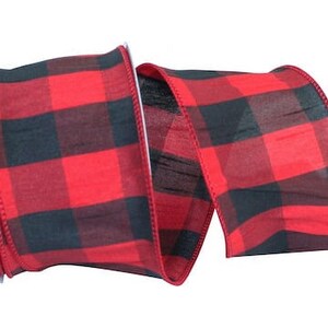 May include: A roll of wide ribbon featuring a bold red and black buffalo check plaid pattern. The fabric has a visible woven texture with finished edges, displayed in a loose, S-shaped curve that shows both the front and inner sides of the material.
