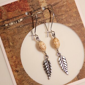 Pendientes colgantes de plumas en tono plateado con cuentas de howlita color crema y marrón imagen 2