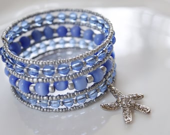 Pulsera con cuentas de alambre de memoria de puño ancho en azul bígaro con ojo de gato y cuentas de vidrio, cuentas de semillas de plata y encanto de estrella de mar con incrustaciones de gemas