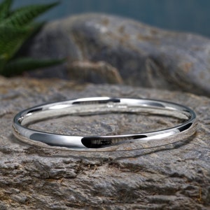 May include: A silver bangle bracelet with a smooth, polished finish. The bracelet is simple and elegant, and would make a great gift.