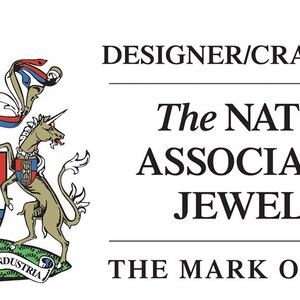 Op de afbeelding: Een logo voor The National Association of Jewellers, met een wapenschild met twee eenhoorns, een schild met een leeuw en de tekst "CONCORDIA-INTEGRITAS INDUSTRIA". De tekst "DESIGNER/CRAFT MEMBER" en "THE MARK OF QUALITY" zijn ook opgenomen.