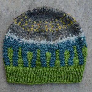 May include: A knitted hat with a grey, yellow, and white patterned top, a blue and green striped middle section, and a solid green bottom.