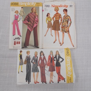 May include: Three vintage Simplicity sewing pattern envelopes. The patterns feature illustrations of women's clothing, including jumpsuits, skirts, and suits. The envelopes are white with colourful illustrations and text. The patterns are from the 1970s.