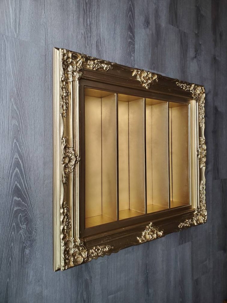 May include: An ornate picture frame in a gold colour with four compartments. The frame is made of wood and has a distressed finish. The compartments are empty.