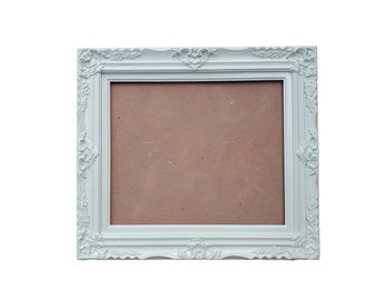May include: White ornate picture frame with a brown mat. The frame has a decorative, detailed design.
