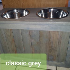 May include: A wooden dog bowl stand with two stainless steel bowls. The stand is painted a classic grey colour.