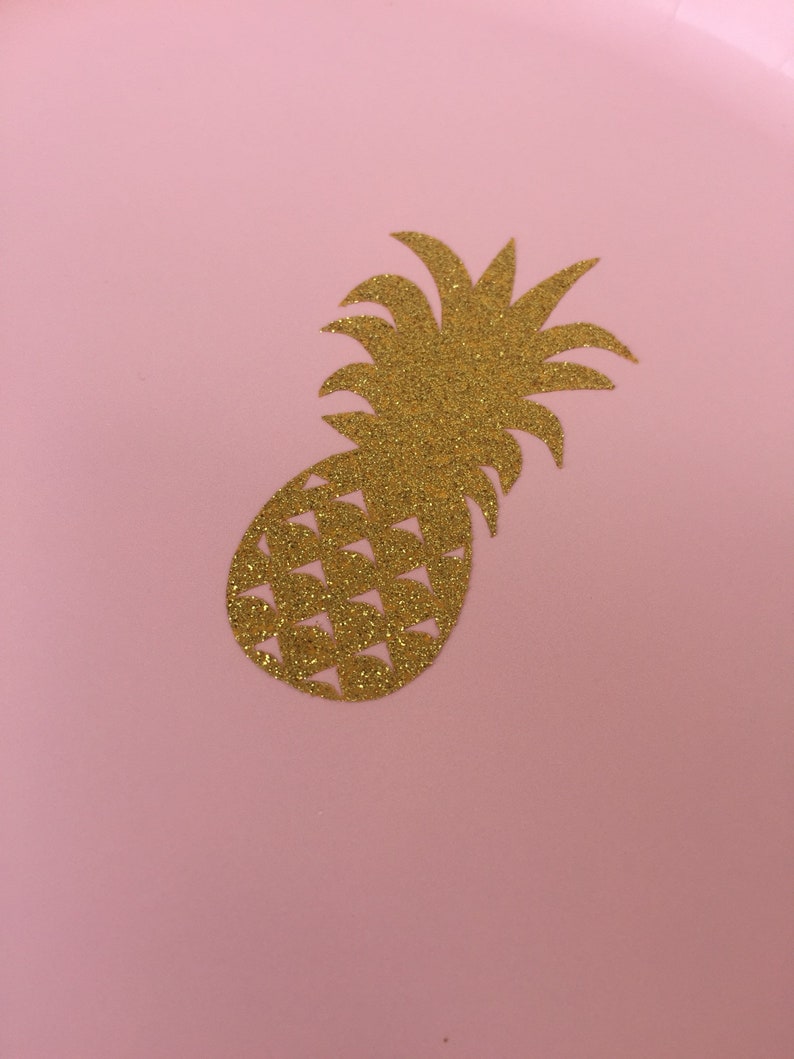 May include: A gold glitter pineapple cutout on a pink background.