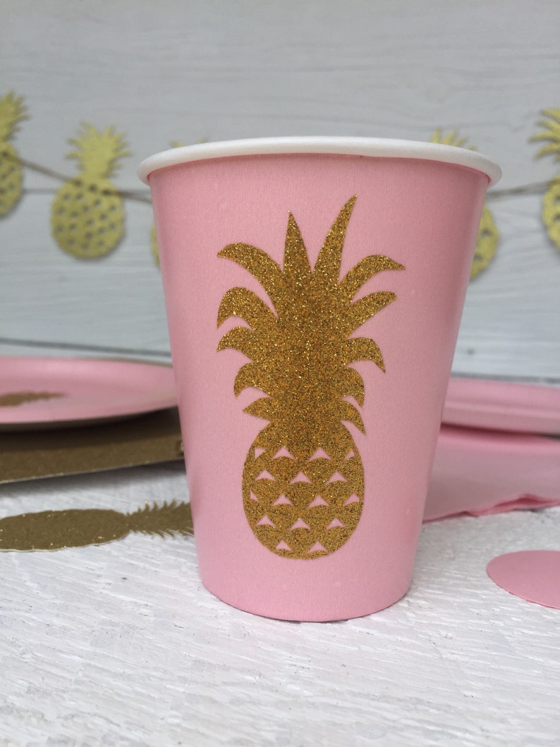 May include: Pink paper cup with a gold glitter pineapple design. The cup is perfect for a tropical themed party.
