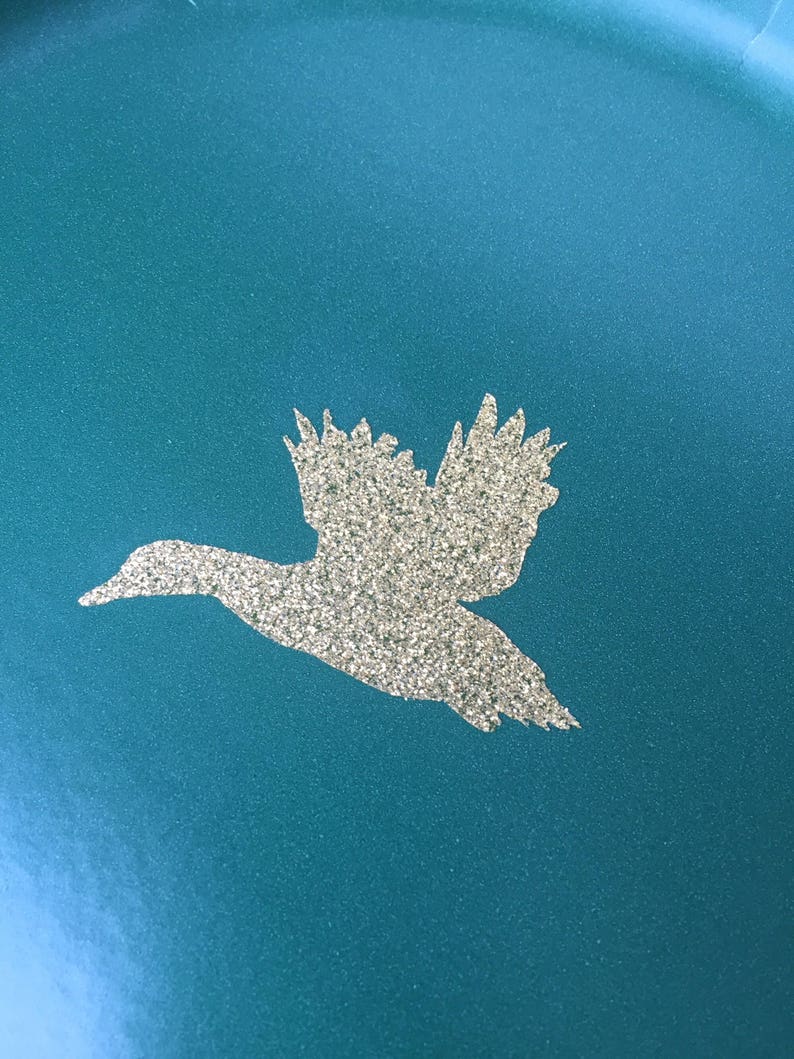May include: A teal blue plate with a silver glitter duck silhouette.