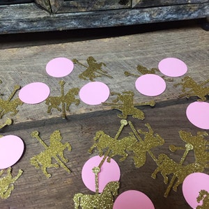 May include: Gold glitter carousel horse cutouts and pink circle confetti scattered on a wooden surface. The carousel horses are in various poses, adding a whimsical touch. Ideal for party decorations or craft projects.