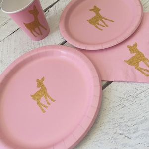 May include: Pink paper plates with gold glitter deer silhouettes.  The plates are part of a party supply set.