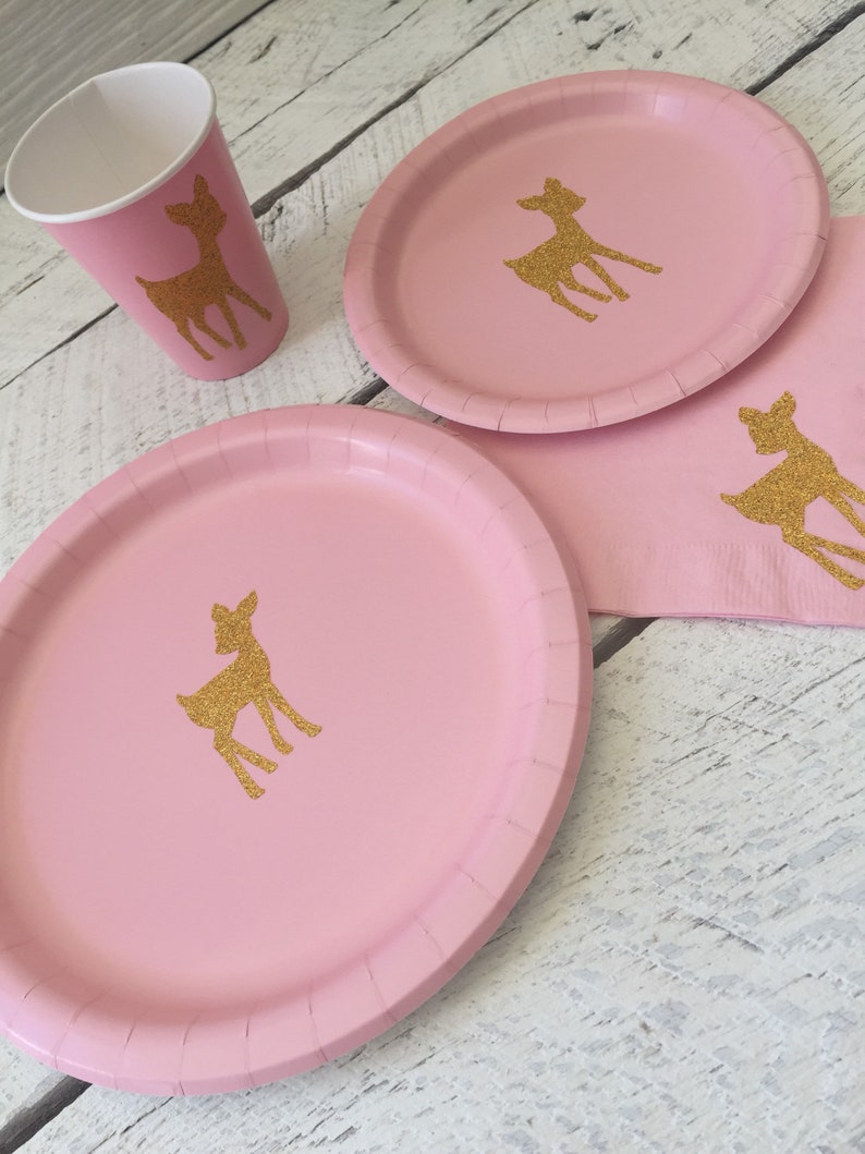 May include: Pink paper plates with gold glitter deer silhouettes.  The plates are part of a party supply set.