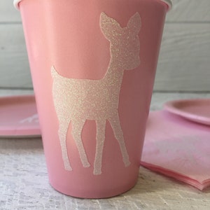 May include: Pink paper cup with a white glitter deer silhouette. The cup is perfect for a party or special occasion.
