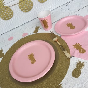 May include: Pink and gold pineapple themed party supplies, including plates, cups, napkins, and a charger. The charger is gold glitter with a pink center.