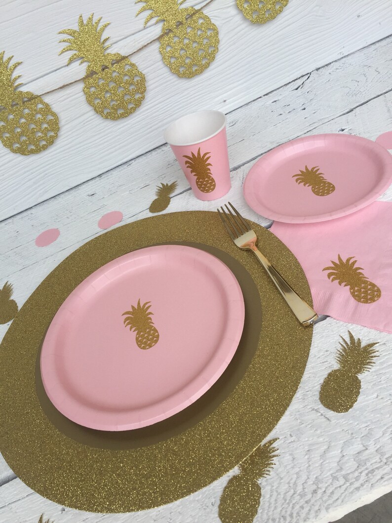 May include: Pink and gold pineapple themed party supplies, including plates, cups, napkins, and a charger. The charger is gold glitter with a pink center.