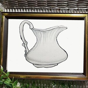 Puede incluir: Ilustración en acuarela enmarcada de una jarra blanca con asa curva y pico acampanado. La obra de arte está enmarcada en un marco plateado adornado con ribete dorado, con vegetación en primer plano.