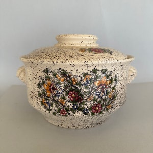 Peut inclure: Un plat de service en céramique blanche avec un motif floral et un glaçage brun moucheté. Le plat a deux poignées sur les côtés et un couvercle.