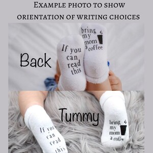 K&ouml;nnte beinhalten: Ein Paar wei&szlig;e Babysocken mit schwarzem Text, der "Wenn du das lesen kannst, bring meiner Mama einen Kaffee" lautet. Die Socken sind an den F&uuml;&szlig;en eines Babys zu sehen, wobei der Text auf der R&uuml;ckseite der F&uuml;&szlig;e nach au&szlig;en und auf der Vorderseite der F&uuml;&szlig;e nach innen gerichtet ist.