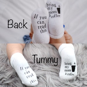 May include: White baby socks with black text that reads "If you can read this bring my mom a coffee" and a coffee cup icon. The socks are on a baby's feet.